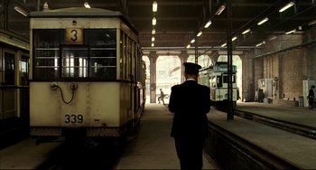 Movie still from “The Reader” (2008), directed by Stephen Daldry – A man standing in front of a train; Wide shot, Low angle