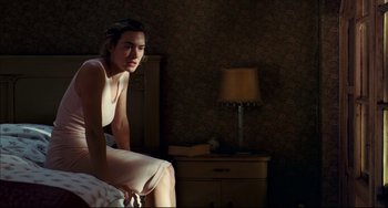 Movie still from “The Reader” (2008), directed by Stephen Daldry – A woman sitting on the edge of a bed in front of a nightstand; Medium shot, High angle
