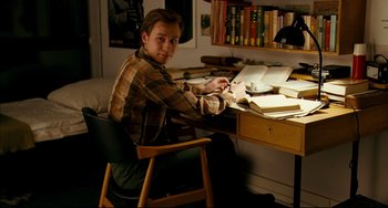 Movie still from “The Reader” (2008), directed by Stephen Daldry – A man sitting at a desk writing on a book; Medium shot, High angle
