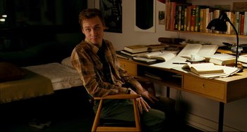 Movie still from “The Reader” (2008), directed by Stephen Daldry – A man sitting at a desk in front of books; Medium shot, High angle