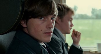 Movie still from “The Reader” (2008), directed by Stephen Daldry – Two young men sitting side - by - side on a train; Close Up shot, Over the shoulder angle