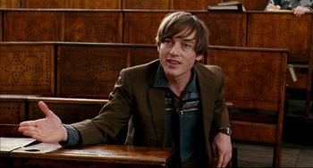 Movie still from “The Reader” (2008), directed by Stephen Daldry – A man sitting at a table wearing a suit and tie; Medium shot, Over the shoulder angle
