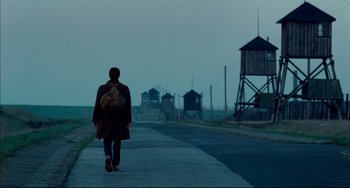Movie still from “The Reader” (2008), directed by Stephen Daldry – A person walking down a road with a backpack; Wide shot, Low angle