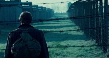 Movie still from “The Reader” (2008), directed by Stephen Daldry – A person with a backpack walking through a field; Wide shot, Over the shoulder angle