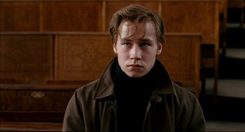Movie still from “The Reader” (2008), directed by Stephen Daldry – A young man in a brown coat is looking at the camera; Close Up shot, Low angle