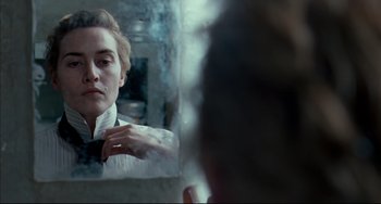 Movie still from “The Reader” (2008), directed by Stephen Daldry – A woman looking in a mirror while holding onto a tie; Close Up shot, Over the shoulder angle