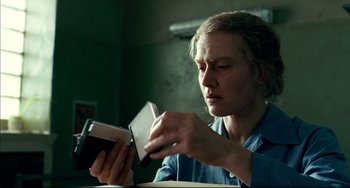Movie still from “The Reader” (2008), directed by Stephen Daldry – A woman is looking at a book with a pen in her hand; Close Up shot, Low angle
