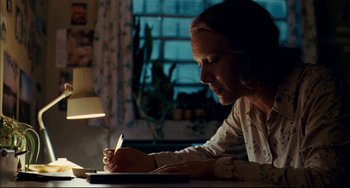 Movie still from “The Reader” (2008), directed by Stephen Daldry – A woman is writing on a piece of paper at a table; Medium shot, Low angle