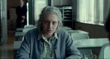 Movie still from “The Reader” (2008), directed by Stephen Daldry – An older woman sitting at a table in front of a window; Medium shot, Over the shoulder angle