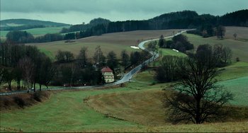 Movie still from “The Reader” (2008), directed by Stephen Daldry – An aerial view of a road and a house in the middle of a field; Extreme Wide shot, High angle