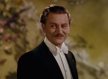 Movie still from “The Red Shoes” (1948), directed by Michael Powell – A man in a suit and bow tie in front of flowers; Close Up shot, Low angle