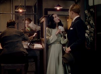 Movie still from “The Red Shoes” (1948), directed by Michael Powell – A woman and a man in a suit and tie talking to each other in a room; Medium shot, Over the shoulder angle