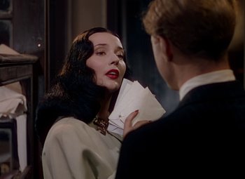 Movie still from “The Red Shoes” (1948), directed by Michael Powell – A man and a woman are holding papers and talking to each other; Close Up shot, Over the shoulder angle