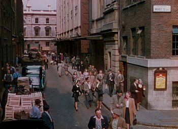 Movie still from “The Red Shoes” (1948), directed by Michael Powell – A group of people walking down a street; Extreme Wide shot, High angle