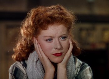 Movie still from “The Red Shoes” (1948), directed by Michael Powell – A woman with red curly hair is holding her hands to her face; Close Up shot, High angle