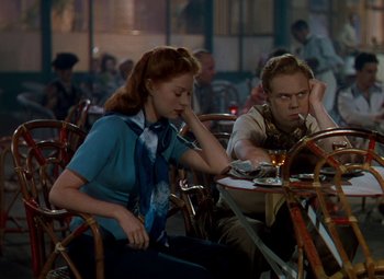 Movie still from “The Red Shoes” (1948), directed by Michael Powell – A woman sitting next to a man at a table; Medium shot, High angle