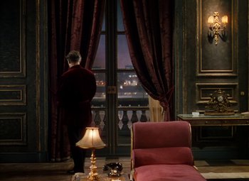 Movie still from “The Red Shoes” (1948), directed by Michael Powell – A man standing in front of a window looking out at a city; Wide shot, High angle