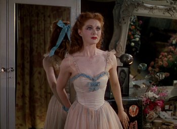 Movie still from “The Red Shoes” (1948), directed by Michael Powell – A woman in a white and blue dress standing in front of a mirror; Medium shot, Over the shoulder angle