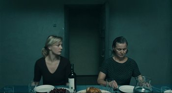 Movie still from “The Return” (2003), directed by Andrey Zvyagintsev – Two women sitting at a dinner table with a bottle of wine; Medium shot, High angle