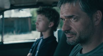 Movie still from “The Return” (2003), directed by Andrey Zvyagintsev – A man and a young boy sitting in the back of a car; Close Up shot, Over the shoulder angle