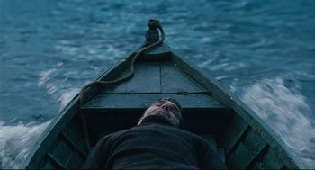Movie still from “The Return” (2003), directed by Andrey Zvyagintsev – A man laying on the back of a boat in the water; Wide shot, High angle
