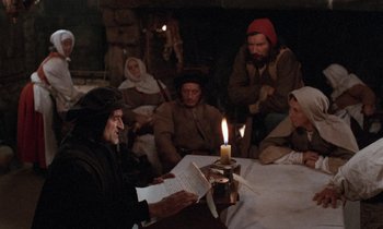 Movie still from “The Return of Martin Guerre” (1982), directed by Daniel Vigne – A group of people sitting around a table with a lit candle; Medium shot, High angle