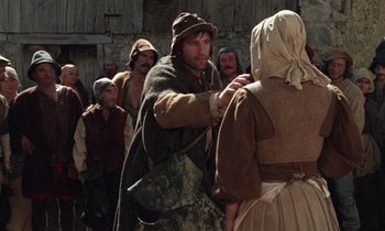 Movie still from “The Return of Martin Guerre” (1982), directed by Daniel Vigne – A group of people standing around a man in a hat; Medium shot, Over the shoulder angle