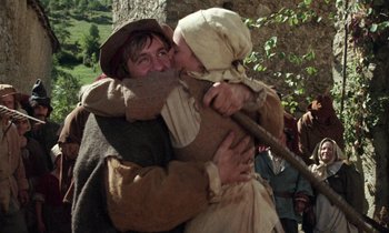 Movie still from “The Return of Martin Guerre” (1982), directed by Daniel Vigne – A man and a woman embracing each other in medieval clothing; Medium shot, Low angle