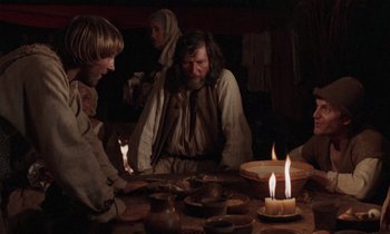 Movie still from “The Return of Martin Guerre” (1982), directed by Daniel Vigne – A group of people sitting around a table with candles on it; Medium shot, Over the shoulder angle