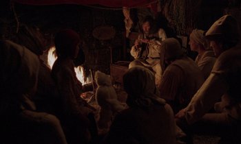 Movie still from “The Return of Martin Guerre” (1982), directed by Daniel Vigne – A group of people sitting around a fire place; Wide shot, High angle