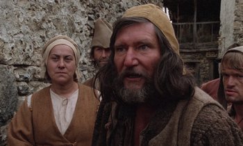 Movie still from “The Return of Martin Guerre” (1982), directed by Daniel Vigne – A group of people standing next to each other near a stone wall; Close Up shot, Over the shoulder angle