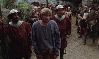 Movie still from “The Return of Martin Guerre” (1982), directed by Daniel Vigne – A group of men in medieval clothing standing in a field; Medium shot, Over the shoulder angle
