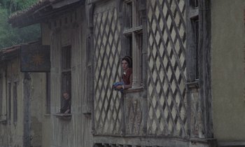 Movie still from “The Return of Martin Guerre” (1982), directed by Daniel Vigne – A man and a woman looking out of a window of an old building; Wide shot, High angle