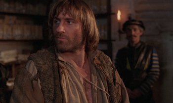 Movie still from “The Return of Martin Guerre” (1982), directed by Daniel Vigne – A man with long hair and a beard wearing a vest; Close Up shot, Over the shoulder angle