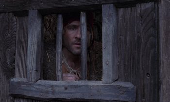 Movie still from “The Return of Martin Guerre” (1982), directed by Daniel Vigne – A man with a beard looking through a fence; Close Up shot, High angle