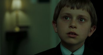 Movie still from “The Ring” (2002), directed by Gore Verbinski – A young boy in a suit and tie looking at the camera; Close Up shot, Over the shoulder angle