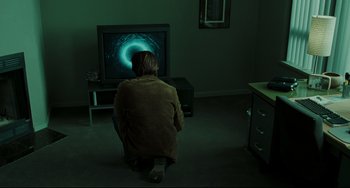Movie still from “The Ring” (2002), directed by Gore Verbinski – A woman sitting in front of a television in a dark room; Wide shot, Over the shoulder angle