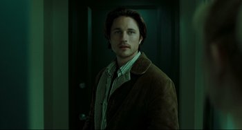 Movie still from “The Ring” (2002), directed by Gore Verbinski – A man standing in front of a door wearing a brown jacket; Close Up shot, Low angle