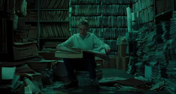 Movie still from “The Ring” (2002), directed by Gore Verbinski – A person sitting on a pile of papers; Wide shot, High angle