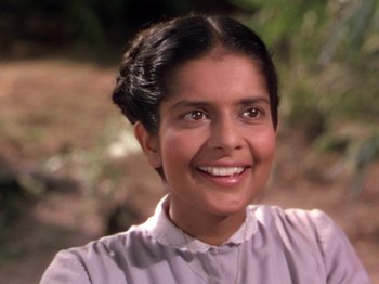Movie still from “The River” (1951), directed by Jean Renoir – A young woman smiling for the camera in front of trees; Close Up shot, High angle