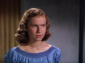 Movie still from “The River” (1951), directed by Jean Renoir – A young woman in a blue dress looking at the camera; Close Up shot, High angle