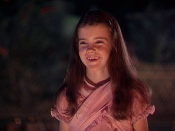 Movie still from “The River” (1951), directed by Jean Renoir – A young girl in a pink dress smiling for the camera; Close Up shot, Low angle