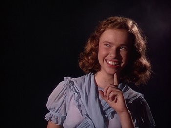 Movie still from “The River” (1951), directed by Jean Renoir – A young woman smiling and holding her finger to her mouth; Close Up shot, Low angle