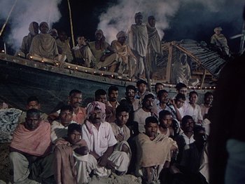 Movie still from “The River” (1951), directed by Jean Renoir – A large group of men sitting on top of a boat; Wide shot, High angle