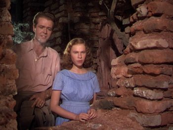 Movie still from “The River” (1951), directed by Jean Renoir – A man and a woman standing next to each other in front of a brick wall; Medium shot, Low angle