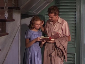 Movie still from “The River” (1951), directed by Jean Renoir – A man and a girl are looking at a book; Medium shot, Low angle
