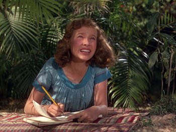 Movie still from “The River” (1951), directed by Jean Renoir – A young girl sitting on the ground with a notebook and pen; Close Up shot, High angle