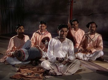 Movie still from “The River” (1951), directed by Jean Renoir – A group of men sitting on the ground in a room; Wide shot, High angle