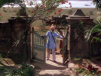 Movie still from “The River” (1951), directed by Jean Renoir – An old man standing at the entrance to a garden; Wide shot, High angle