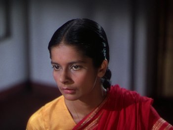 Movie still from “The River” (1951), directed by Jean Renoir – A woman in a yellow and red sari looks into the camera; Close Up shot, High angle